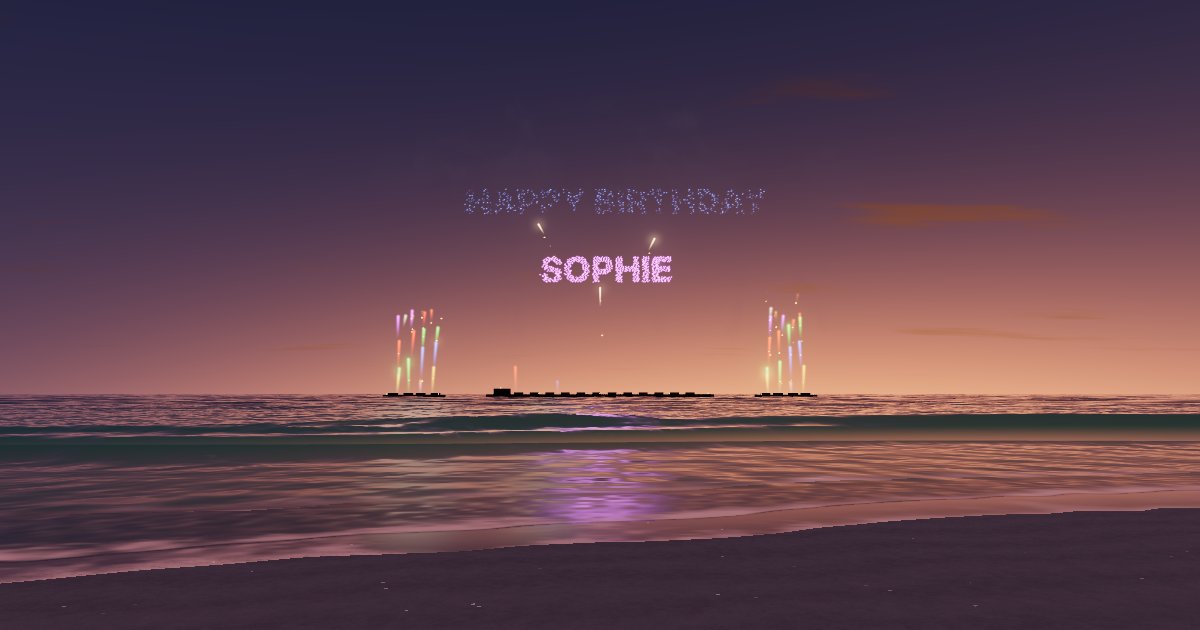 HAPPY BIRTHDAY above the name SOPHIE, spelled in firework sparks over a beach with fountains on the barges